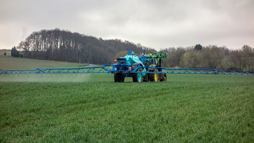 Traktor som besprutar åker med konstgödsel