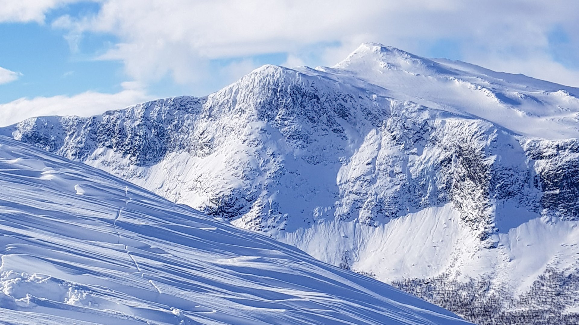 Vinterfjäll, snö och blå himmel.